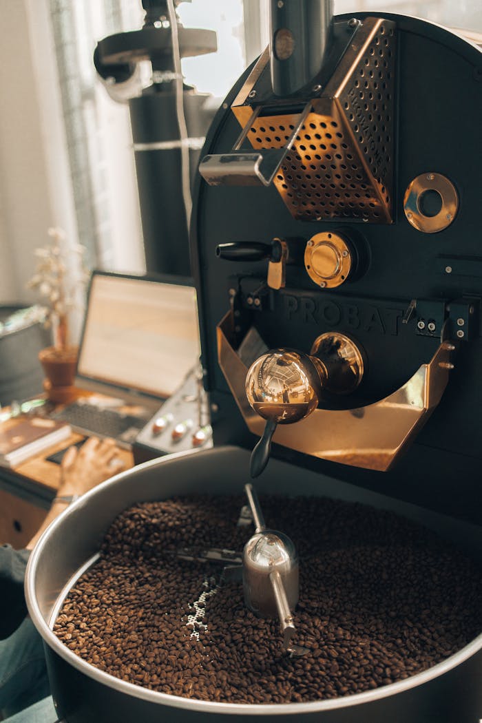 our-services-1 Coffee roasting machine with laptop and decor in modern indoor setting.